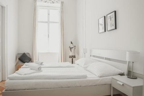 a white bedroom with a white bed and a window at HeyMi Apartments Stephansdom in Vienna