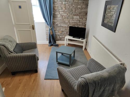 a living room with two chairs and a tv at Kings Arms Hotel in Kirkby Lonsdale