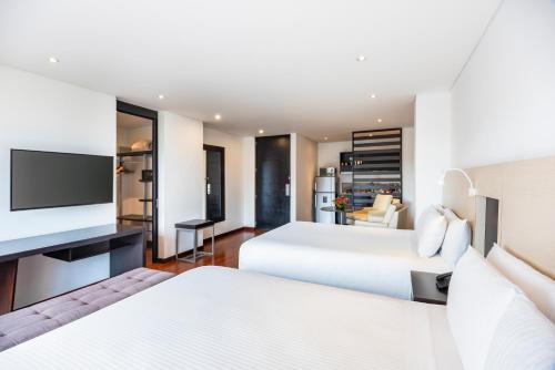 a hotel room with two beds and a flat screen tv at Hotel Jazz Apartments in Bogotá