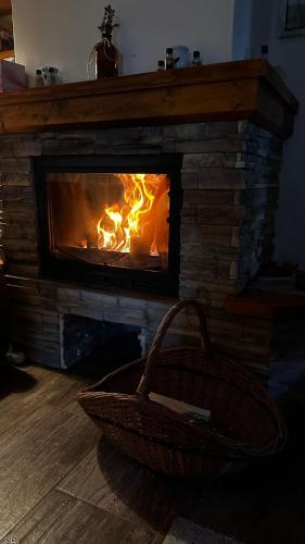 a fire burning in a fireplace with a basket in front of it at Újhegy Apartman in Gyarmat