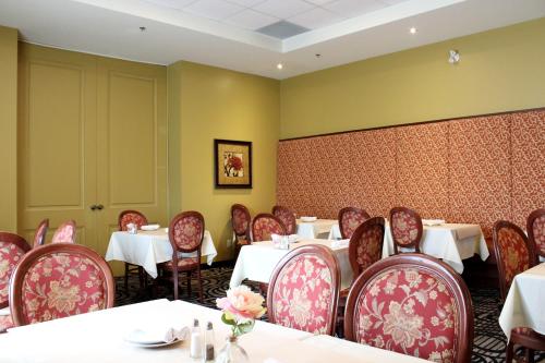 a dining room with white tables and red chairs at Monte Carlo Inn & Suites Downtown Markham in Markham