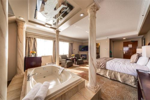 Monte Carlo Inn & Suites Downtown Markham في ماركهام: غرفة نوم مع سرير وحوض استحمام في غرفة