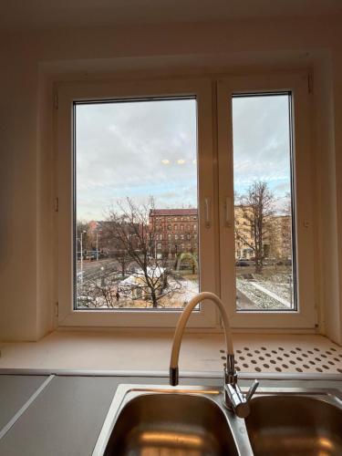 a kitchen window with a sink and a view of a city at BEMA Guest House - City Centre in Wrocław