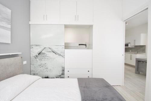 um quarto branco com uma cama e uma cozinha em Vistamare Apartments em Jesolo