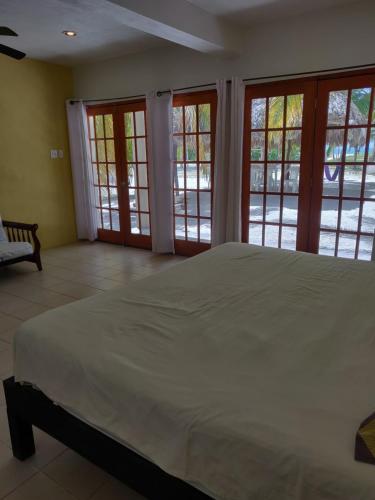 a bedroom with a large white bed and windows at Villas Del Mar in Celestún