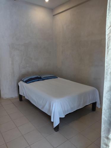 a bed with white sheets and blue pillows in a room at Villas Del Mar in Celestún