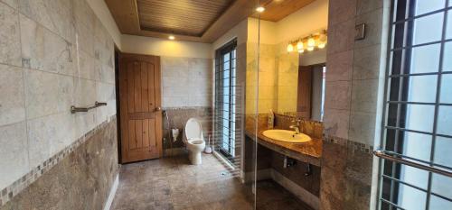 a bathroom with a toilet and a sink and a mirror at Haven Lodge Bhurban, 6BR Holiday Home in Hill Station in Bhurban