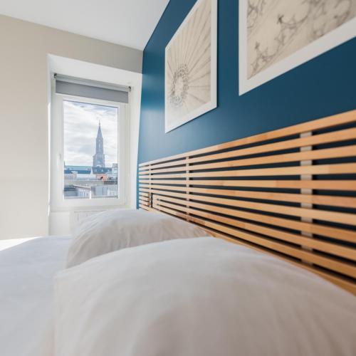 une chambre avec un grand lit et une fenêtre dans l'établissement Studios de la Nuée Bleue, à Strasbourg