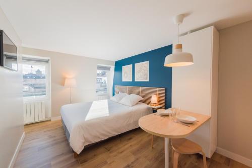 een slaapkamer met een groot bed en een tafel bij Studios de la Nuée Bleue in Straatsburg