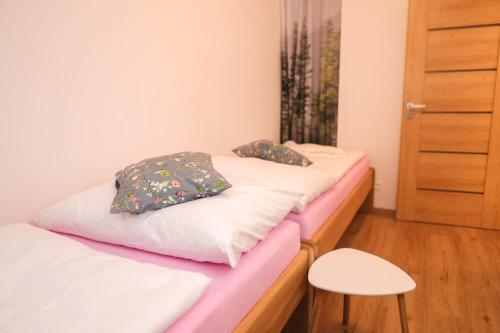 2 Betten in einem kleinen Zimmer mit einem Hocker in der Unterkunft Mandala in Jáchymov