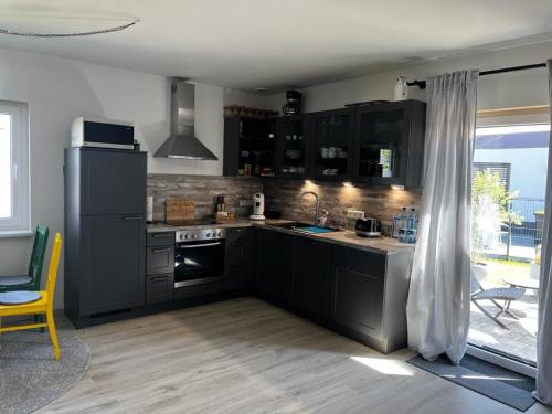 een keuken met zwarte kasten en een fornuis met oven bij Work and Stay Erlensee in Erlensee
