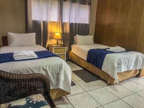 a bedroom with two beds and a chair and a lamp at Leribisi Lodge in Tierpoort