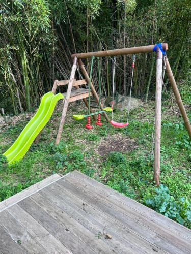 un parque infantil con un tobogán y dos columpios en Maison de vacances vue mer en Calcatoggio