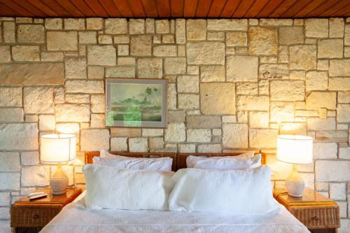 a bedroom with a stone wall with a bed and two lamps at Frenchman's Cove Resort in Port Antonio