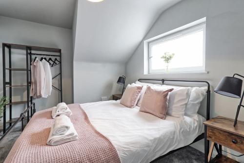 a bedroom with a bed with white sheets and pink pillows at Deluxe Large Three Room Apartment by Southend Stays in Southend-on-Sea