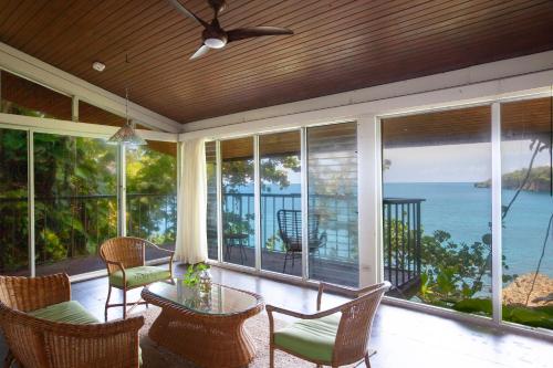 a screened in porch with a table and chairs and the ocean at Frenchman's Cove Resort in Port Antonio