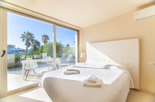 a bedroom with a white bed and a large window at Playa Blanca Zahara in Zahara de los Atunes