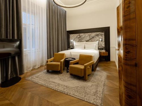 a hotel room with a bed and two chairs at Hotel Collect - Adults Only in Budapest