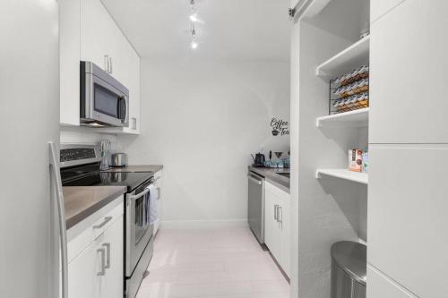 a kitchen with white cabinets and a microwave at The Hidden Gem, King bed & Swimming Pool! in Chandler