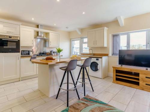 a kitchen with white cabinets and a counter with stools at 3 Bed in Lampeter 86506 in Cellan