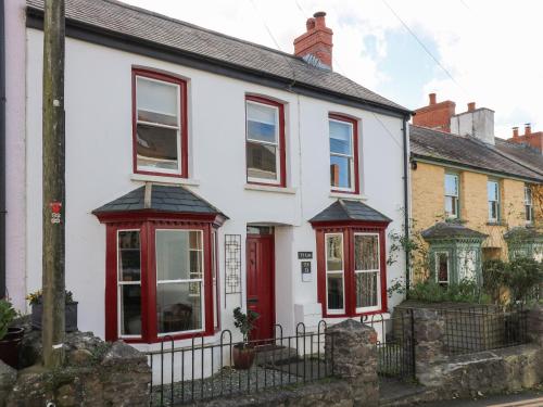 a white house with red windows and a red door at Ty Len in Haverfordwest