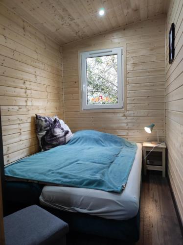 Cama en habitación de madera con ventana en Unser Großer - Tiny House 