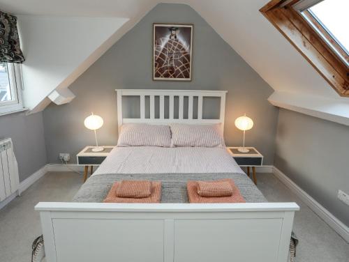 a bedroom with a large white bed with two lamps at 5 Craig Y Mor in Pwllheli