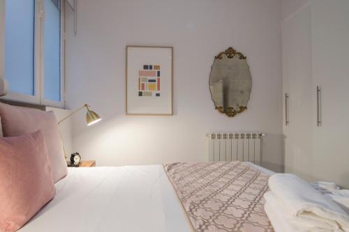 Schlafzimmer mit einem Bett mit weißer Bettwäsche und rosa Kissen in der Unterkunft APARTAMENTO EN SANTA ANA - SOL (2H + 2B) in Madrid