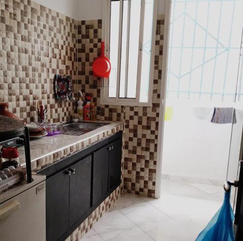 uma cozinha com um lavatório e uma bancada em Qamar's guests 4 em Al Hoceïma