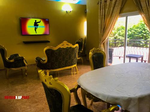 uma sala de estar com uma mesa e cadeiras e uma televisão em Hôtel appartement luxe em Foumban