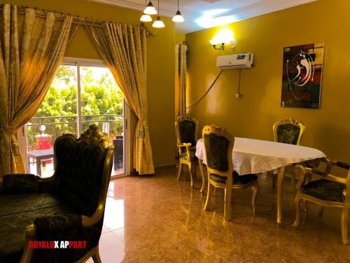 een eetkamer met een tafel en stoelen en een raam bij Hôtel appartement luxe in Foumban