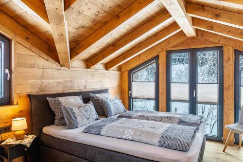 Bett in einem Zimmer mit Holzwänden und Fenstern in der Unterkunft Chalet Aus Holz in Garmisch-Partenkirchen