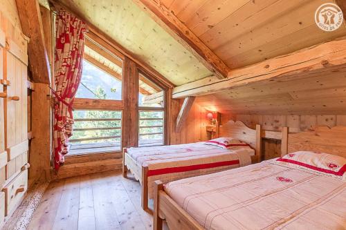 a bedroom with two beds in a wooden cabin at Chalet de Marie proche des Saisies in Queige