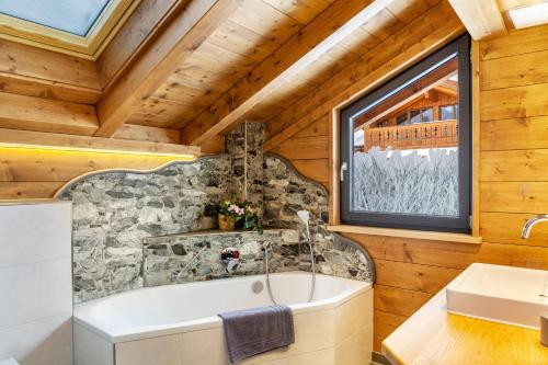 a bathroom with a tub and a stone wall at Chalet Aus Holz in Garmisch-Partenkirchen