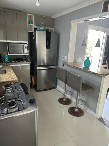 a kitchen with a stainless steel refrigerator and a stove at EXCELENTE Apto COM SUITE in Capão da Canoa