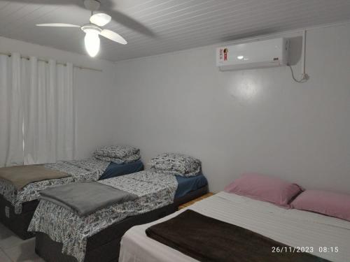 een kamer met 3 bedden en een plafondventilator bij Casa com wi-fi - Próxima à Universidade e Oktoberfest in Marechal Cândido Rondon