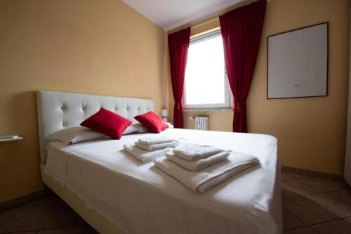 ein Schlafzimmer mit einem Bett mit weißen Decken und roten Kissen in der Unterkunft Casa Verena in Aosta