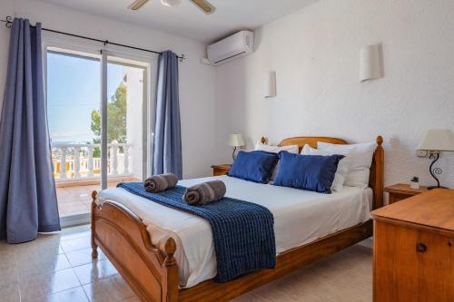 una camera da letto con un letto con cuscini blu e una finestra di Villa Moggalatto by Villa Plus a Calpe