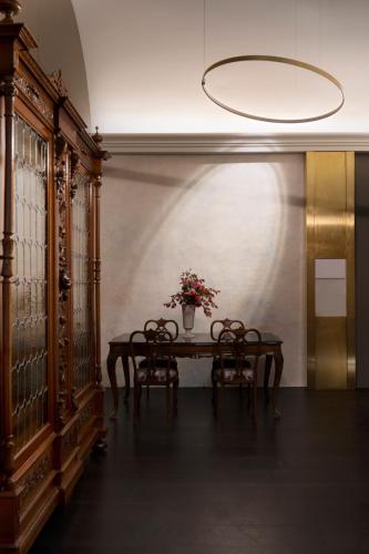 a dining room with a table with chairs and a vase with flowers at Palazzo Giusti Suites and Spa in Urbino
