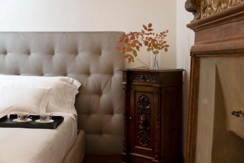 a bedroom with a bed and a wooden night stand with two glasses at Palazzo Giusti Suites and Spa in Urbino