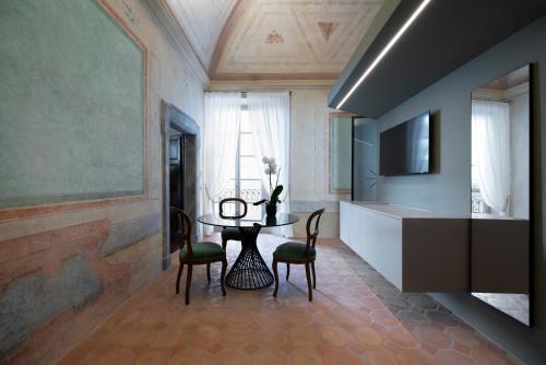 a dining room with a table and chairs and a television at Palazzo Giusti Suites and Spa in Urbino