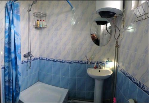 La salle de bains bleue et blanche est pourvue d'un lavabo et d'une douche. dans l'établissement Janat Family Guesthouse, à Karakol