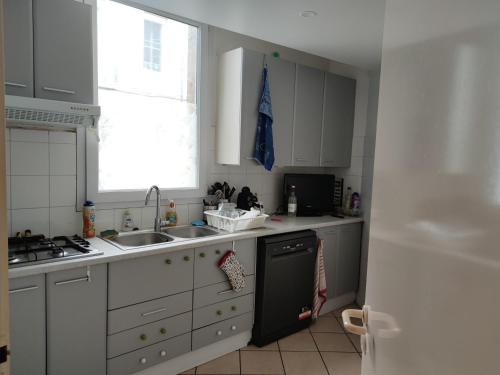 una cucina con armadi bianchi, lavandino e finestra di A Bordeaux, Climatisée avec billard a Le Bouscat