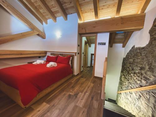 Un dormitorio con una cama roja en una habitación con techos de madera. en Aux Pieds du Malatra' 1, en Saint-Rhémy-en-Bosses