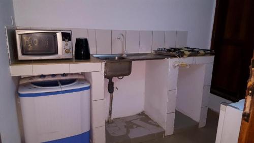 a small kitchen with a sink and a microwave at 2 chambres salon Baguida in Lomé
