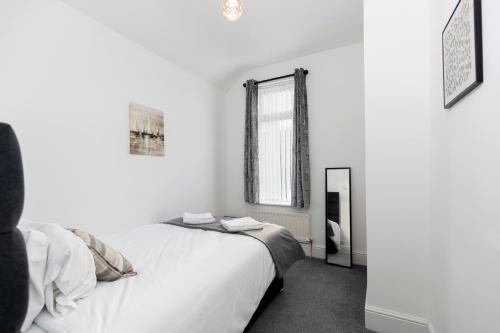 a white bedroom with a bed and a mirror at Bright House in Hartlepool