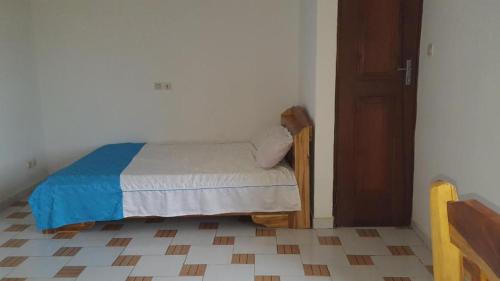 a small bed in a room with a door at 2 chambres salon Baguida in Lomé