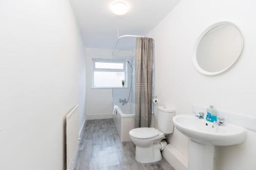 a white bathroom with a toilet and a sink at Bright House in Hartlepool