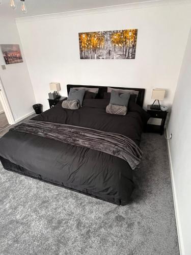 a bedroom with a large bed with black sheets at Eden Stays in Stivichall