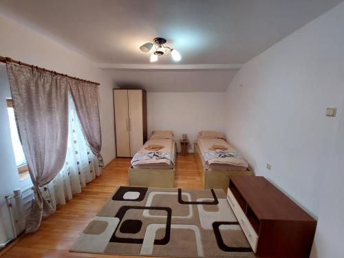 een kamer met 2 bedden, een tafel en een raam bij Casa Auraș 